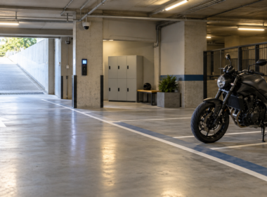 Moto sin marcas aparcada en una plaza amplia de un parking cubierto, con acceso, taquillas e iluminación visibles