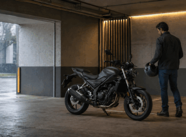 Motorista junto a una moto aparcada bajo techo mientras llueve en el exterior