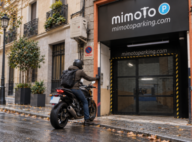 Motorista ante la entrada cerrada de MimoTo Parking Chamberí, con logotipo y señalética, en un día de otoño